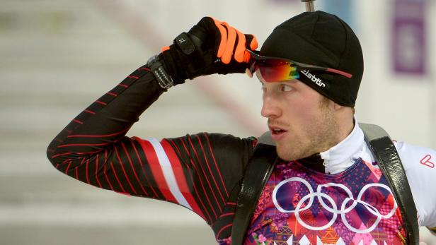 Ein Biathlet mit Mütze und Skibrille blickt konzentriert in die Ferne.