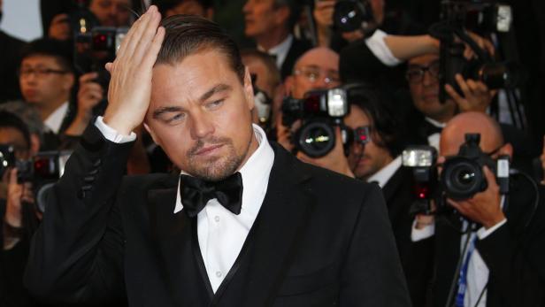 Leonardo DiCaprio posiert auf einem roten Teppich vor einer Gruppe von Fotografen.