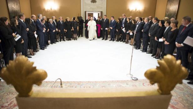 Papst Franziskus trifft sich mit einer Gruppe von Menschen in einem formellen Raum.