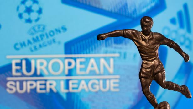 A metal figure of a football player with a ball is seen in front of the words "European Super League" and the UEFA Champions League logo in this illustration