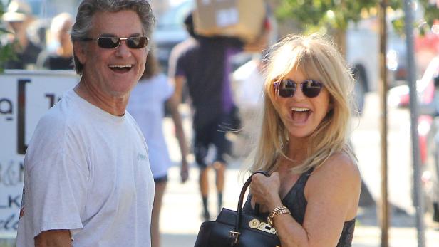 Goldie Hawn und Kurt Russell lachen zusammen auf der Straße.