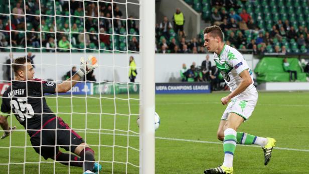 Ein Fußballspieler schießt aufs Tor, während der Torwart versucht, den Ball abzuwehren.