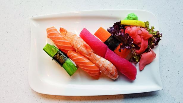 Eine Platte mit verschiedenen Sushi-Sorten, darunter Lachs, Garnele und Thunfisch.