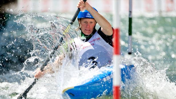 Eine Frau paddelt in einem blauen Kajak durch einen Wildwasserkanal.