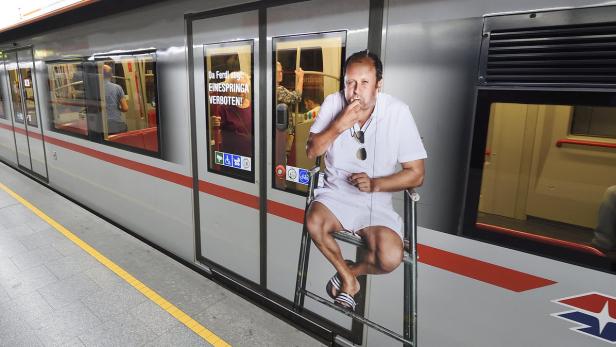 Eine Werbung in einer U-Bahn zeigt eine Person, die auf einer Leiter sitzt und etwas isst.