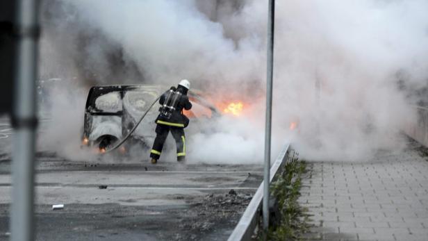 Ein Feuerwehrmann löscht einen brennenden Lieferwagen, der in Rauch gehüllt ist.