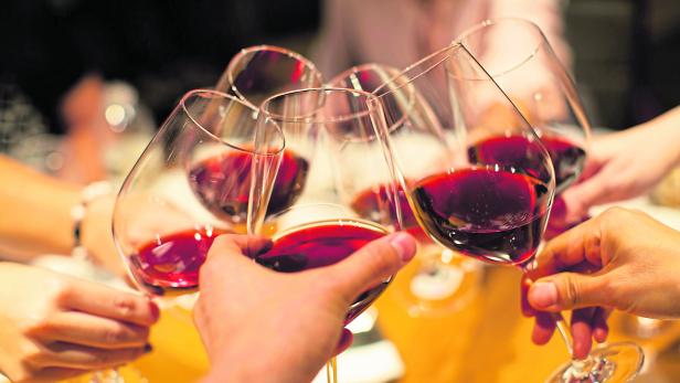 Group of Friends Celebrating Toasting Wine Glasses. Business Meeting Cheers. Symbol of Friendship or Family Celebration. Fine Dining at Luxury Restaurant.  Red Wine in Glasses. Diverse People.