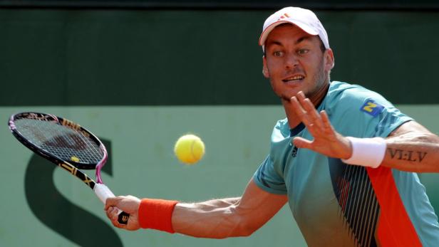 Ein Tennisspieler schlägt einen gelben Ball mit seinem Schläger.