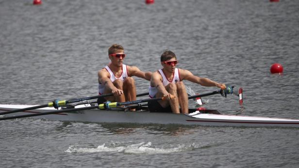 Zwei Ruderer mit Sonnenbrillen in einem Rennboot auf dem Wasser.