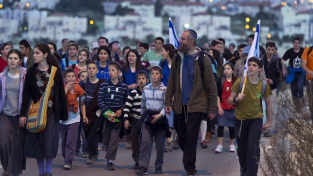 Eine Gruppe jüdischer Jugendlicher marschiert mit israelischen Flaggen durch eine Stadt.