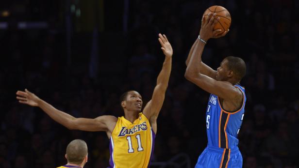 Ein Basketballspieler der Oklahoma City Thunder wirft den Ball, während ein Spieler der Los Angeles Lakers ihn verteidigt.