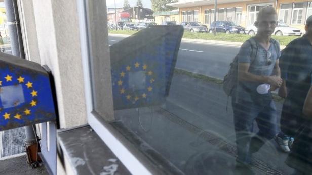 Drei junge Männer gehen an einem Schild der Europäischen Union vorbei.