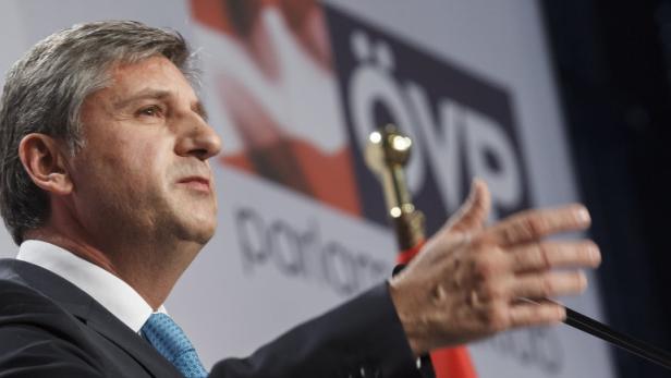 Ein Mann in Anzug spricht vor einem ÖVP-Banner.