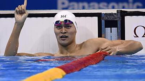 Ein Schwimmer im Becken mit Badekappe und Schwimmbrille reckt den Zeigefinger in die Höhe.