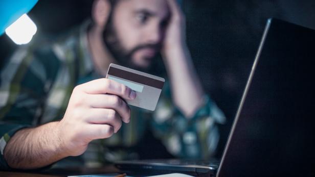 Close-up of a man paying bills from home by using a laptop and a credit card