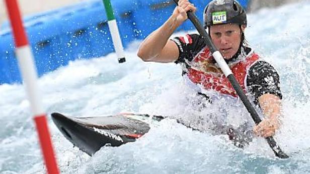 Eine Kanutin mit Helm und Paddel kämpft sich durch das Wildwasser.