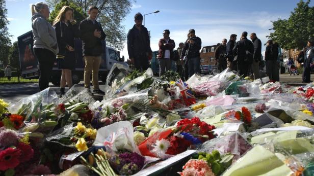 People view flowers left outside an army barracks near the scene of a killing in Woolwich, southeast London May 23, 2013. British authorities believe that two men accused of hacking a soldier to death on a London street in revenge for wars in Muslim countries are British of Nigerian descent, a source close to the investigation said Thursday. REUTERS/Luke MacGregor (BRITAIN - Tags: CRIME LAW MILITARY POLITICS)