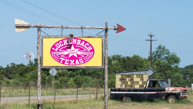 Ein Schild mit der Aufschrift „Luckenbach Texas“ und ein alter Pickup-Truck.