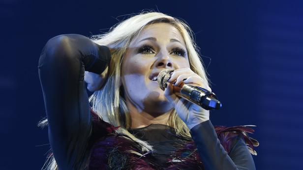 Helene Fischer singt in einem schwarzen Federkleid ins Mikrofon.