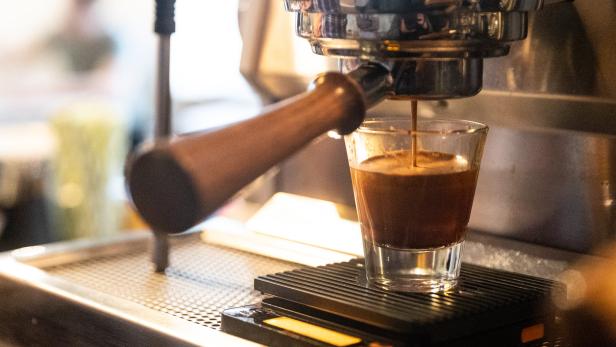 Eine Espressomaschine füllt ein kleines Glas mit frisch gebrühtem Kaffee.