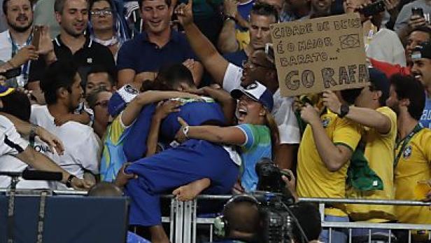 Jubelnde brasilianische Fans feiern einen Judoka bei einem Wettkampf.