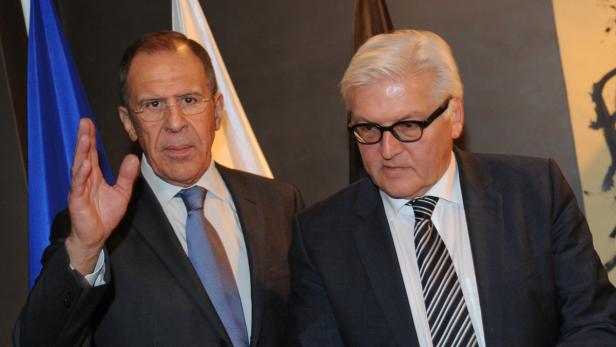 Sergej Lawrow und Frank-Walter Steinmeier stehen nebeneinander vor Flaggen.
