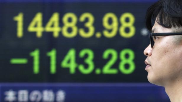 Ein Mann blickt auf eine Anzeigetafel mit Börsenkursen.