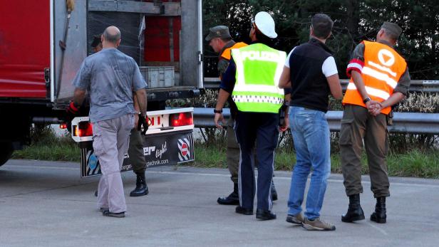 Mehrere Personen, darunter ein Polizist, stehen an einem Lastwagen.