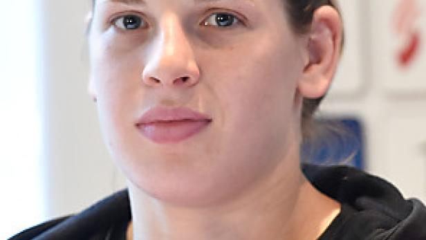 Porträt einer jungen Frau in Sportkleidung mit dem österreichischen Wappen.