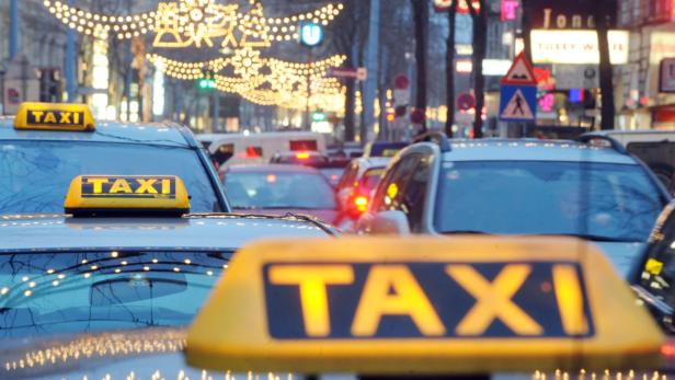 Mehrere Taxis stehen auf einer belebten Straße mit Weihnachtsbeleuchtung.