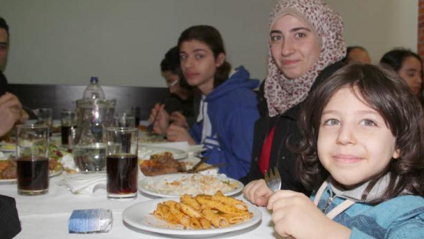 Eine Gruppe von Menschen sitzt an einem Tisch mit Speisen und Getränken.