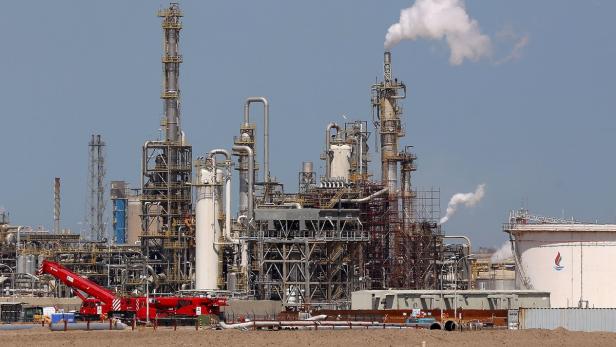 Eine große Industrieanlage mit Türmen, Rohren und einem roten Kran im Vordergrund.