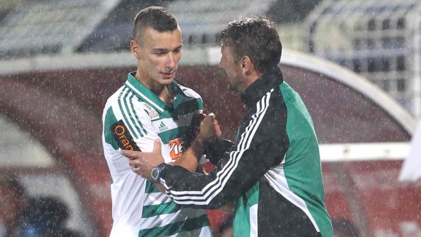 Ein Fußballspieler und sein Trainer unterhalten sich im Regen.