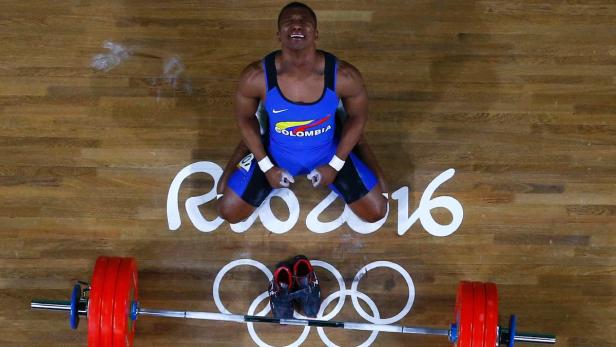 Ein Gewichtheber aus Kolumbien kniet erschöpft nach dem Wettkampf auf der Bühne.