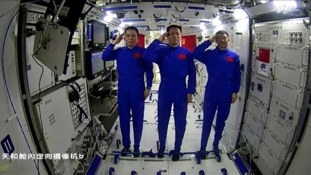 Chinese astronauts Nie Haisheng, Liu Boming and Tang Hongbo of the Shenzhou-12 mission salute as they speak to Chinese President Xi Jinping via a video call