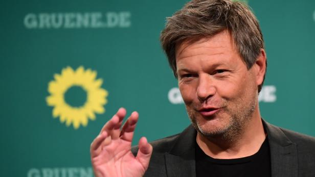 Robert Habeck gestikuliert vor einem grünen Hintergrund mit dem Logo der Grünen.