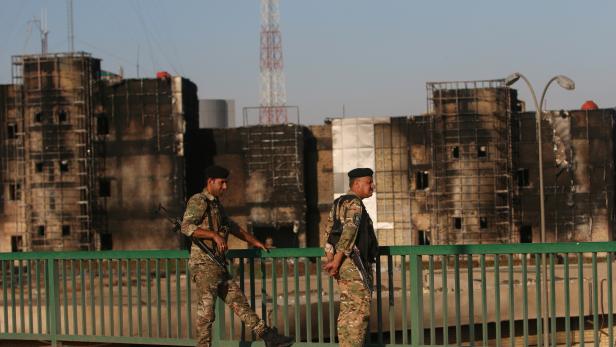 Members of Iraqi police stand guard in front of Maysan Governorate building, which was burnt by demonstrators during a protest over unemployment, corruption and poor public services, in Maysan province, south of Bagdad