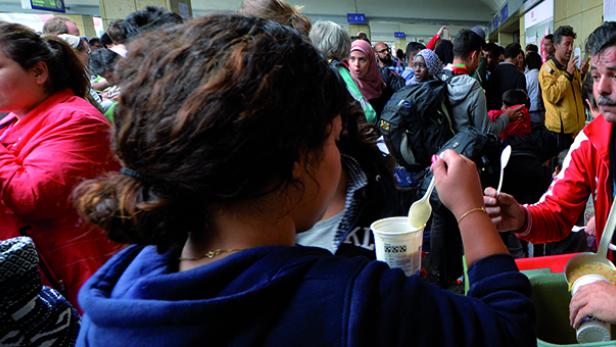 Menschen erhalten an einem Bahnhof Essen.