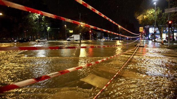Eine überflutete Straße in der Nacht, abgesperrt mit rot-weißem Flatterband.