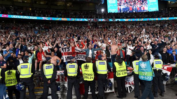 Eine jubelnde Menschenmenge bei der UEFA EURO 2020, bewacht von Polizisten und Stewards.