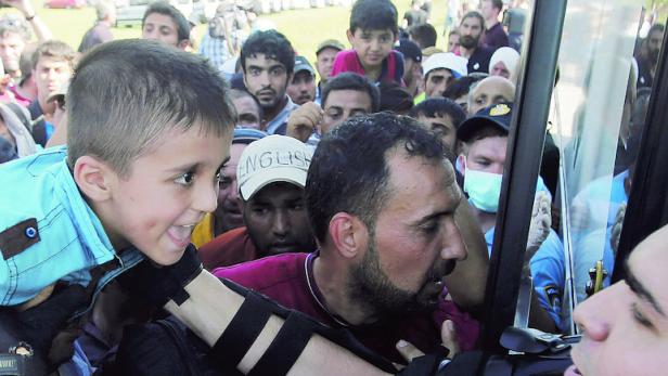 Weiter, weiter Richtung Norden wollen diese Flüchtlinge, die in der kroatischen Grenzstadt Tovernik einen Bus stürmen. Ein Polizist hilft dabei einem Buben