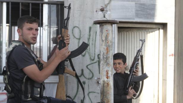 A Free Syrian Army fighter and a boy hold up weapons on a street at the Syrian town of Tel Abyad, near the border with Turkey, April 23, 2013. Picture taken April 23, 2013. REUTERS/Hamid Khatib (SYRIA - Tags: POLITICS CIVIL UNREST CONFLICT SOCIETY)