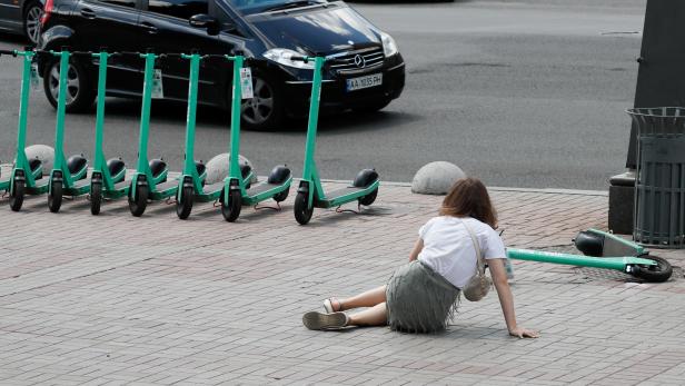 A woman lies on the ground after falling off an e-scooter in central Kyiv