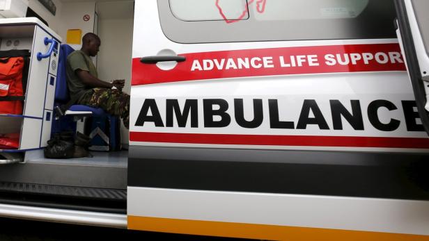 Ein Sanitäter sitzt in einem Krankenwagen mit der Aufschrift „Ambulance“.