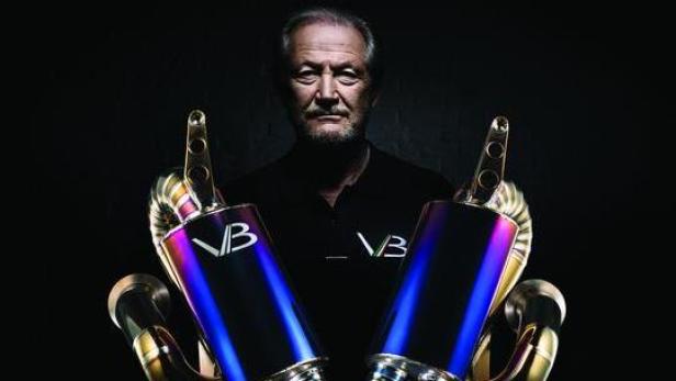 Ein Mann hält zwei farbige Auspuffrohre der Marke VB in seinen Händen.