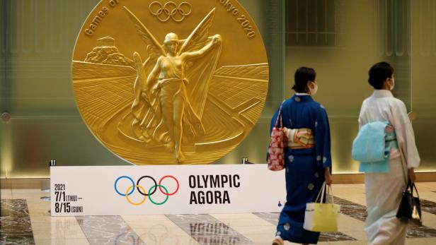Women walk past a large-scale reproduction of Tokyo 2020 Olympic Games medal at Nihonbashi Mitsui Tower in Tokyo Women walk past a large-scale reproduction of Tokyo 2020 Olympic Games medal at Nihonbashi Mitsui Tower in Tokyo