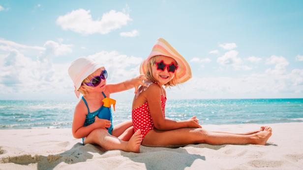 sun protection, cute girls with sun cream at beach