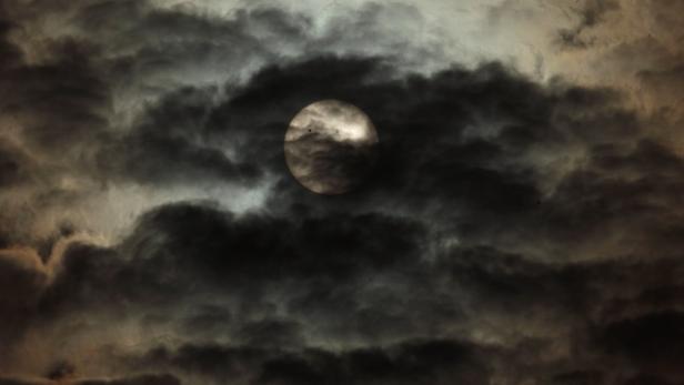 Die Sonne scheint durch dunkle Wolken.