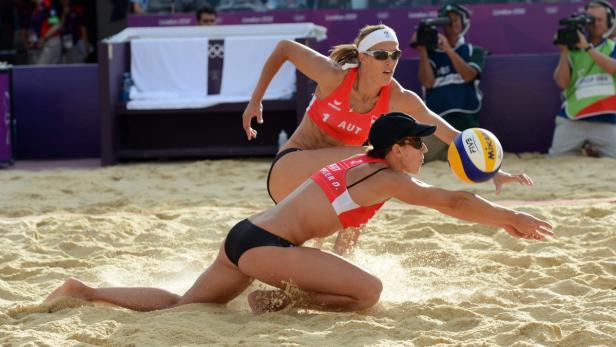 Zwei Beachvolleyballspielerinnen aus Österreich bei einem Spiel im Sand.