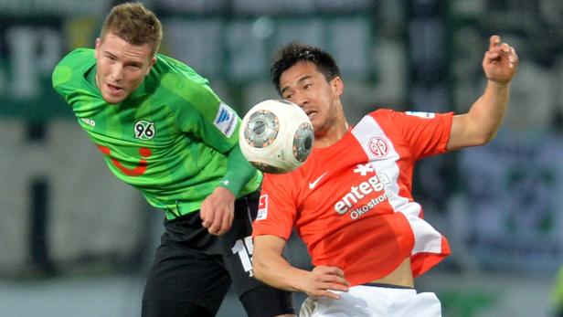 Zwei Fußballspieler kämpfen um den Ball während eines Spiels.